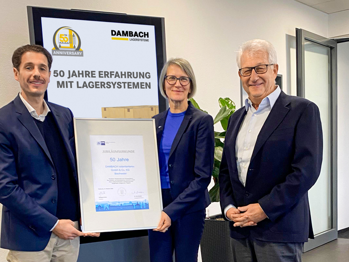 Drei Personen präsentieren gemeinsam die 50 Jahre DAMBACH Urkunde in einem Büro